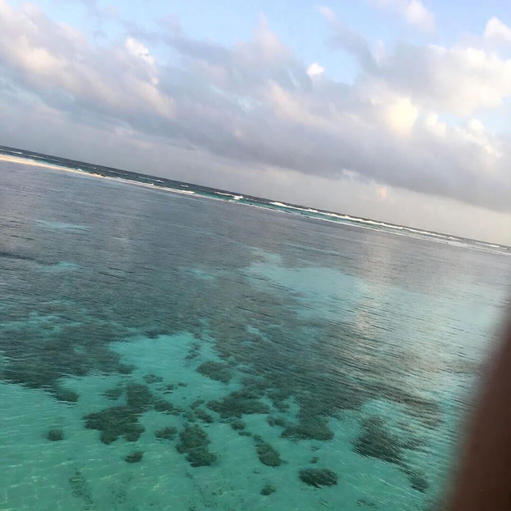 Serene empty turquoise beach with reef shadows.