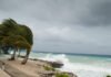 Beach Destinations to Avoid (and Enjoy) During Hurricane Season Humorous stormy beach with quirky crab escaping hurricane season chaos