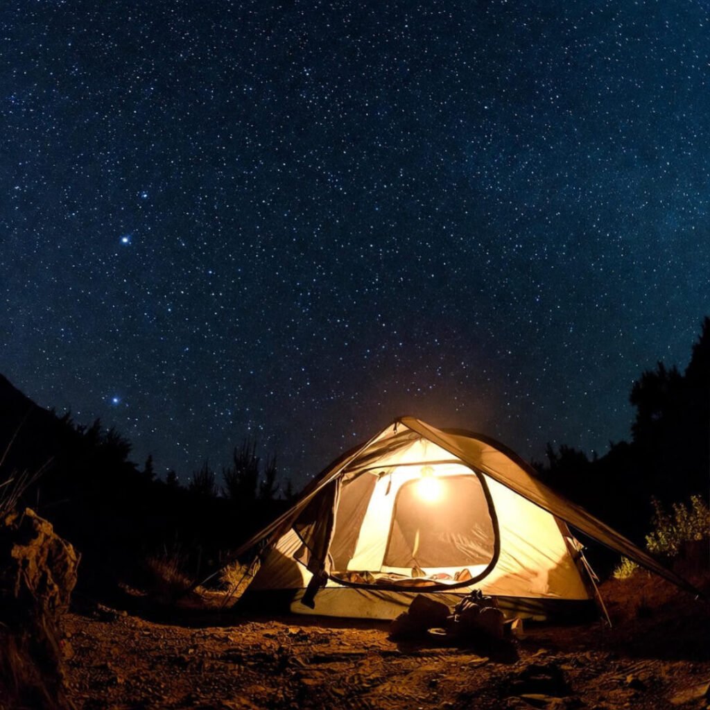 Starry night over lit glamping tent with footprints.