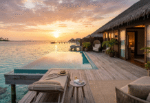 Overwater villa with infinity pool at golden hour sunset.
